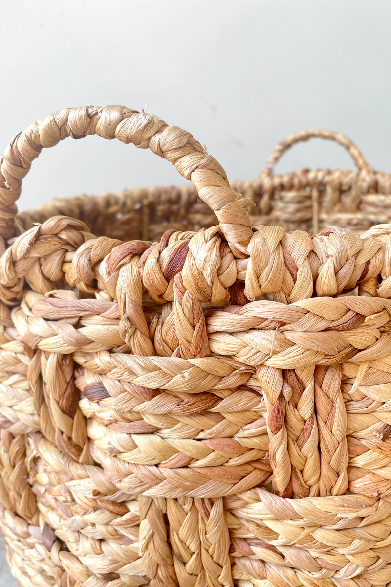 A close-up view of the large Handwoven Seagrass & Metal Basket with handles against a white backdrop