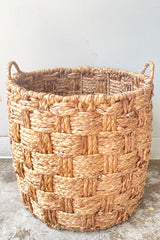 A frontal view of the large Handwoven Seagrass & Metal Basket with handles against a white backdrop