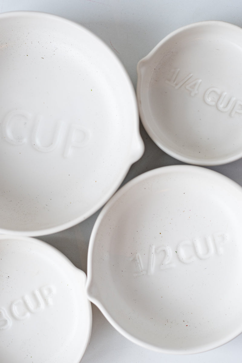 White circular Stoneware Measuring Cup Set spread out against a white background