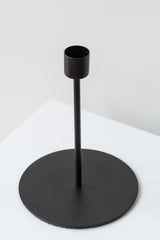 Black tall taper candle holder on a white surface in a white room