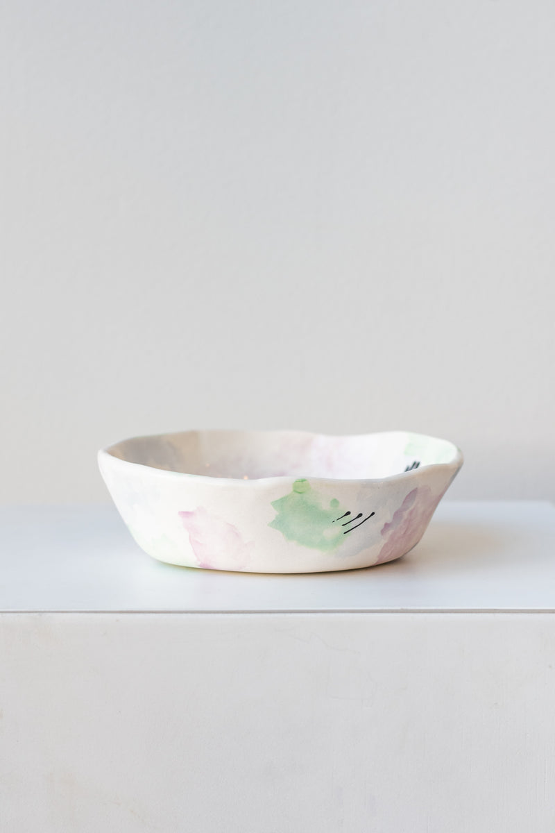 Technicolor Dino handpainted porcelain small bowl on a white surface in a white room
