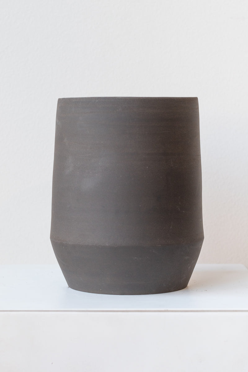 Megan Suave Ceramics large black stoneware vase on a white surface in a white room