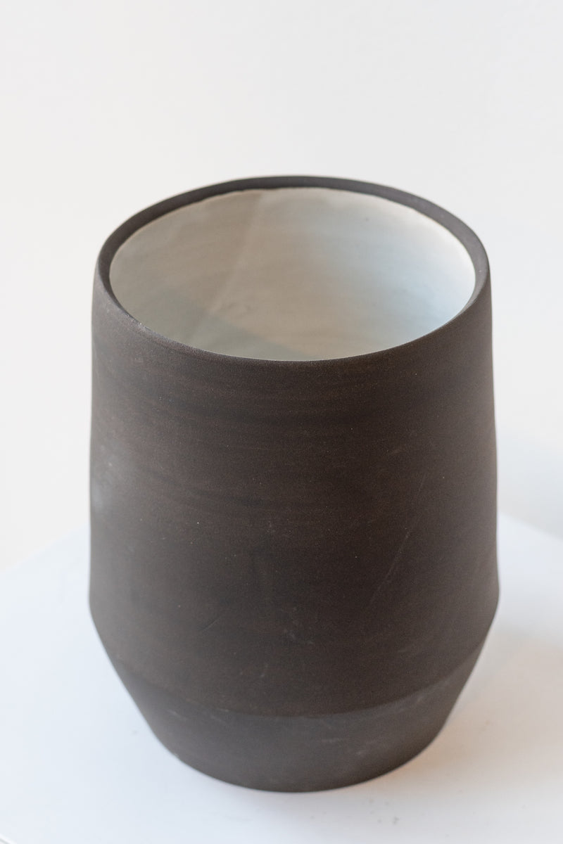 Megan Suave Ceramics large black stoneware vase on a white surface in a white room