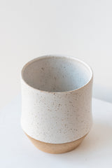 Megan Suave Ceramics small speckle stoneware vase on a white surface in a white room