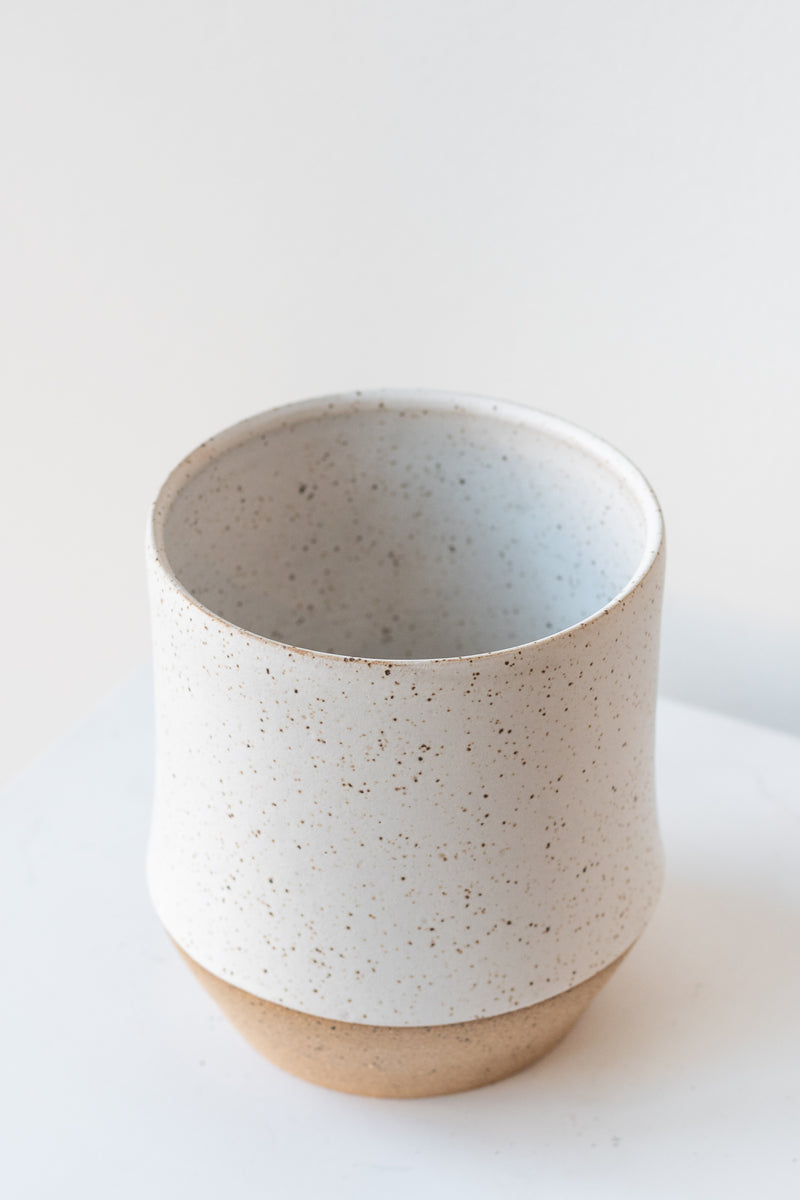 Megan Suave Ceramics small speckle stoneware vase on a white surface in a white room