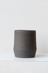 Megan Suave Ceramics small black stoneware vase on a white surface in a white room