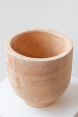 Small footed terra cotta planter by Hawkins New York on a white surface in a white room