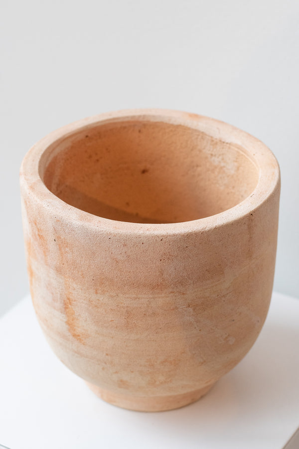 Small footed terra cotta planter by Hawkins New York on a white surface in a white room