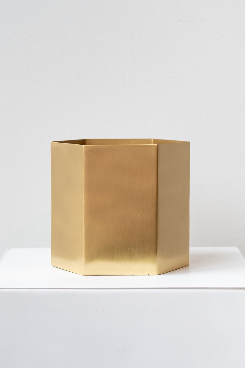 Brass hexagon-shaped plant pot by Ferm Living in front of white background