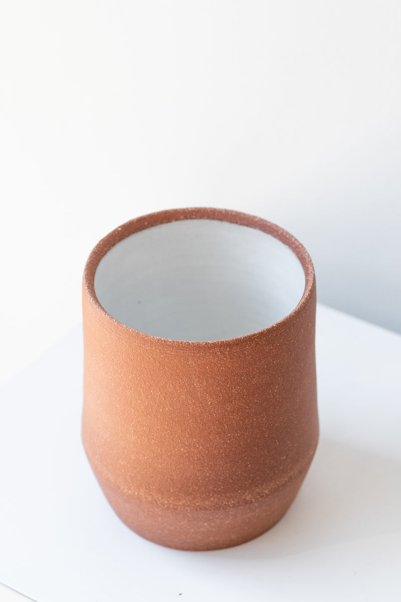 Megan Suave Ceramics small brick stoneware vase on a white surface in a white room