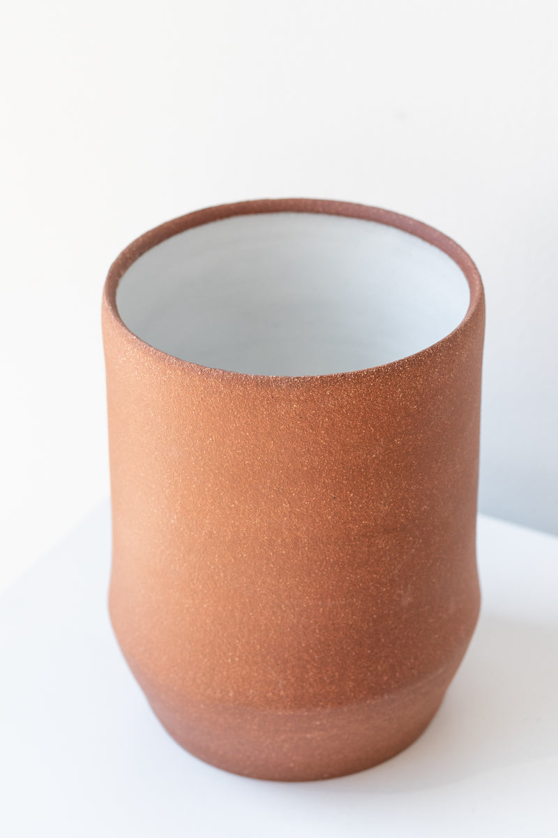 Megan Suave Ceramics large brick stoneware vase on a white surface in a white room