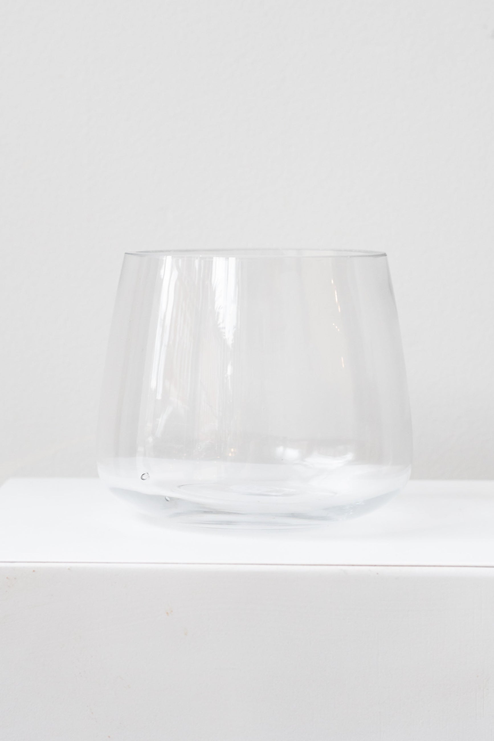 A clear glass vase with a round bottom and a reverse taper shape, displayed against a white background. ©Sprout Home
