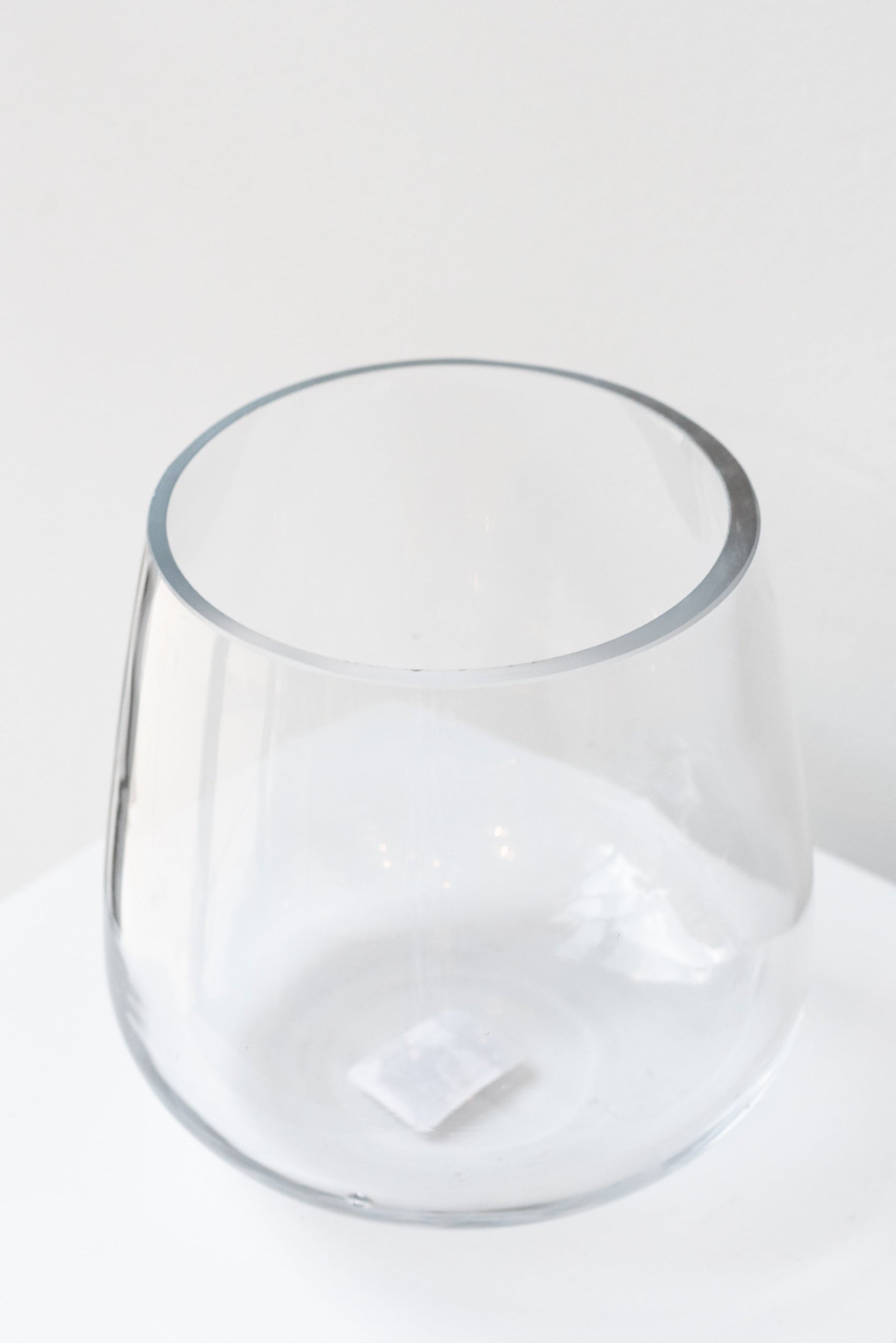 Round bottomed clear glass vase sitting on a white surface, empty ©Sprout Home