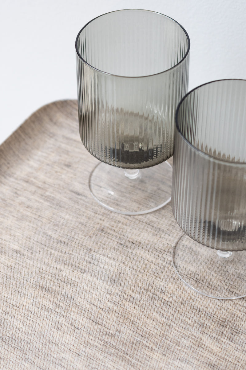 Two rippled grey wine glasses on top of natural linen coated serving tray by Fog Linen