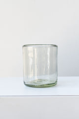 Recycled hand-blown rocks tumbler glass on white surface in a white room