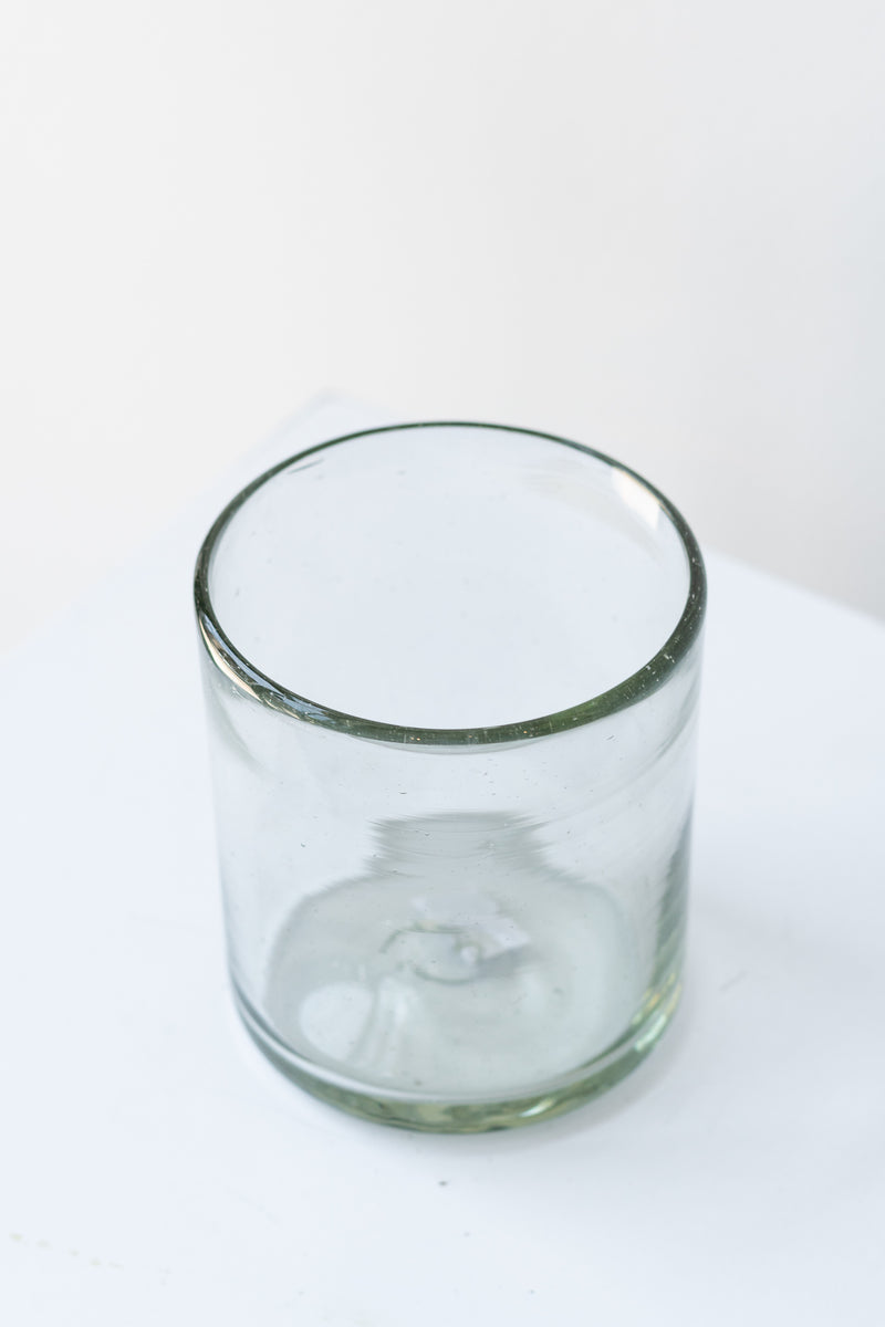 Recycled hand-blown rocks tumbler glass on white surface in a white room