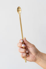 Fog linen work brass muddler spoon held in front of white background