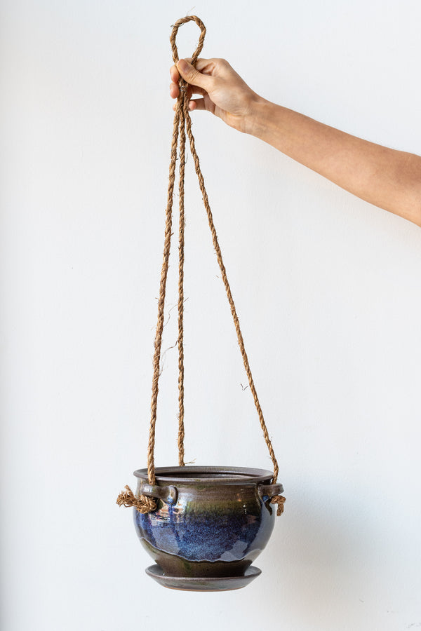 Bruning Pottery Hanging Planter moss & lilac glaze - 6" held in front of white wall