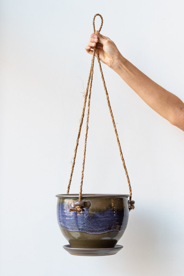 Bruning Pottery Hanging Planter moss & lilac glaze - 8" held in front of white wall