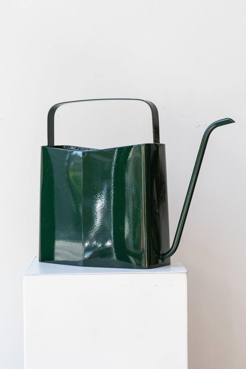 Modern evergreen watering can by Modern Sprout on white pedestal in front of white background