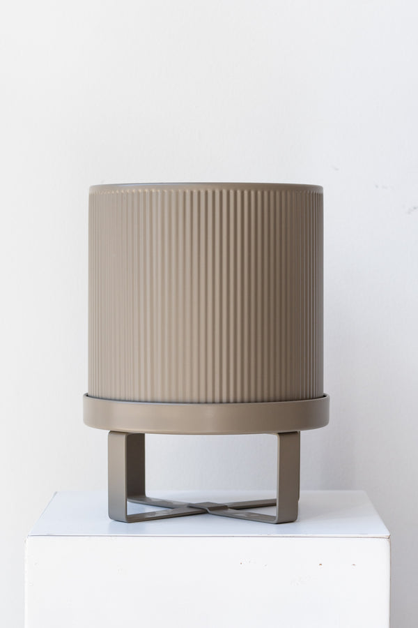 Small warm grey Bau Pot by Ferm Living on a white pedestal in front of white background