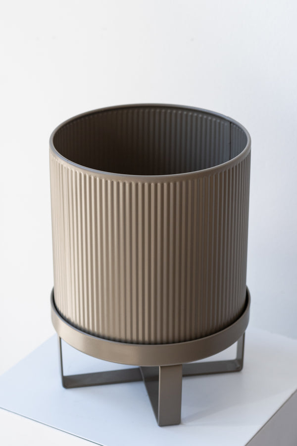 Small warm grey Bau Pot by Ferm Living on a white pedestal in front of white background