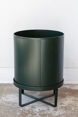 Large dark green Bau Pot by Ferm Living on a concrete floor in front of white background