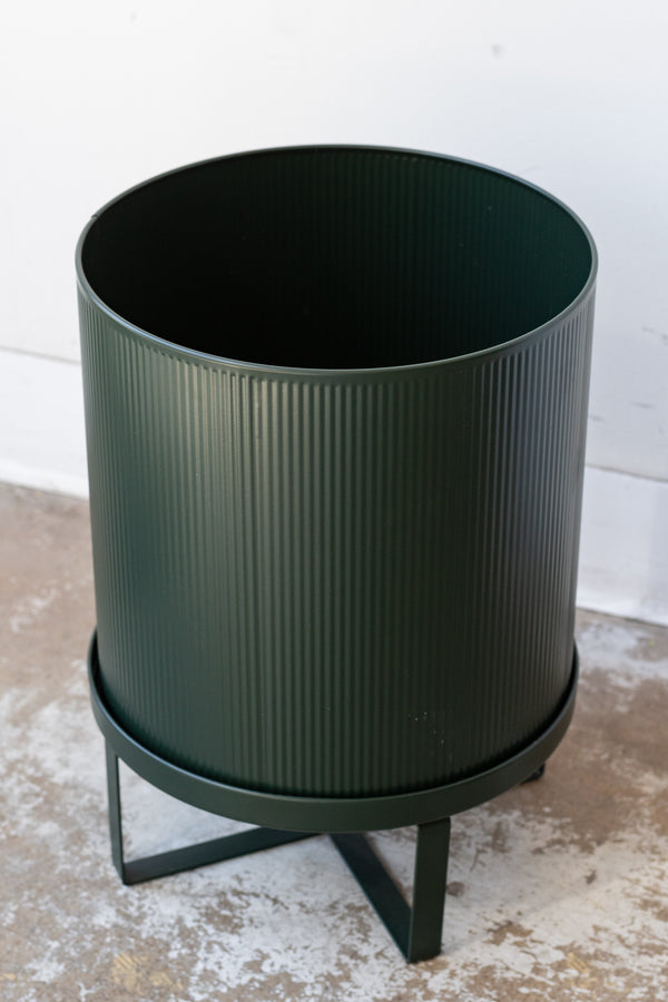 Large dark green Bau Pot by Ferm Living on a concrete floor in front of white background