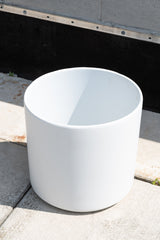 LBE Designs Solid Cylinder white 12” outside in front of concrete brick wall