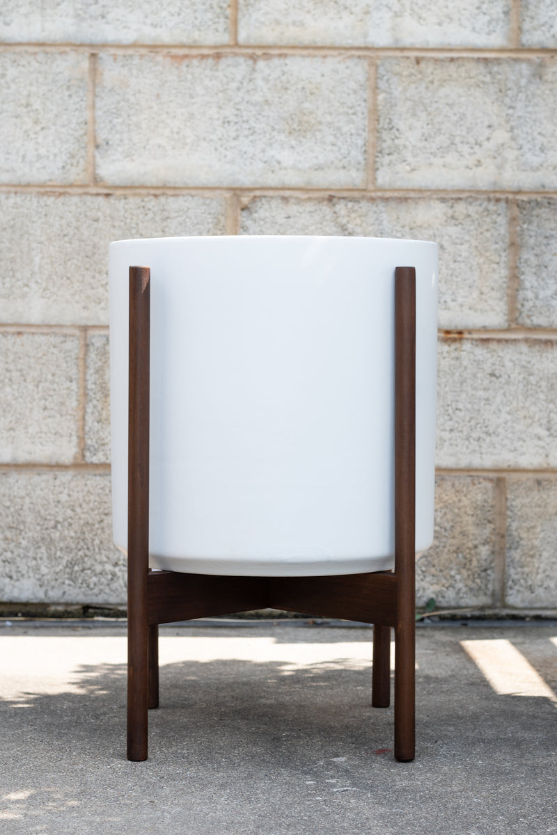 LBE Designs Stoneware Cylinder & Dark Teak Stand white 12” in front of concrete brick wall