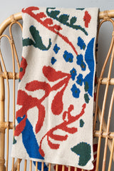 Poppies and lotus flax blanket by Hillery Sproatt draped over wicker chair