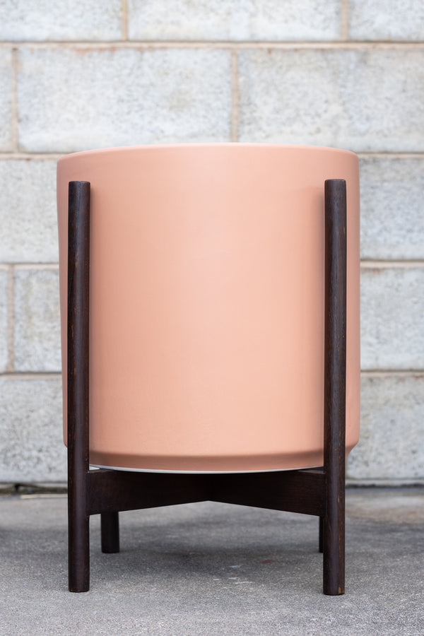 LBE Designs The 14 Cylinder & Dark Teak Stand peach in front of concrete wall