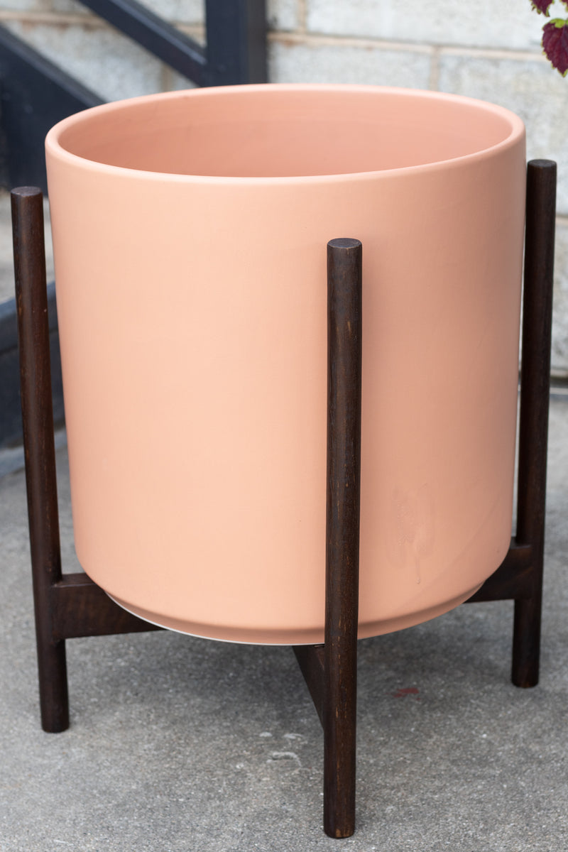 LBE Designs The 14 Cylinder & Dark Teak Stand peach in front of concrete wall