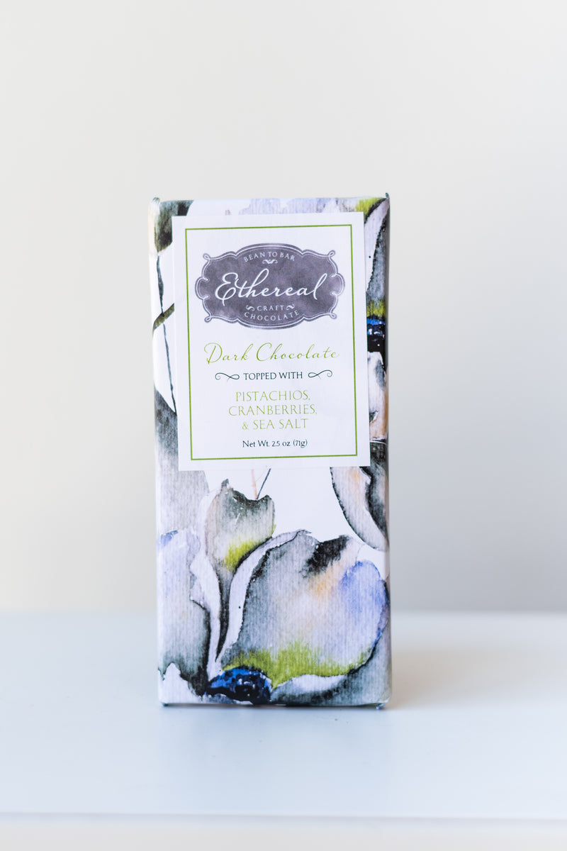 Ethereal Chocolate dark chocolate bar with pistachios, cranberries, and sea salt on a white surface in a white room