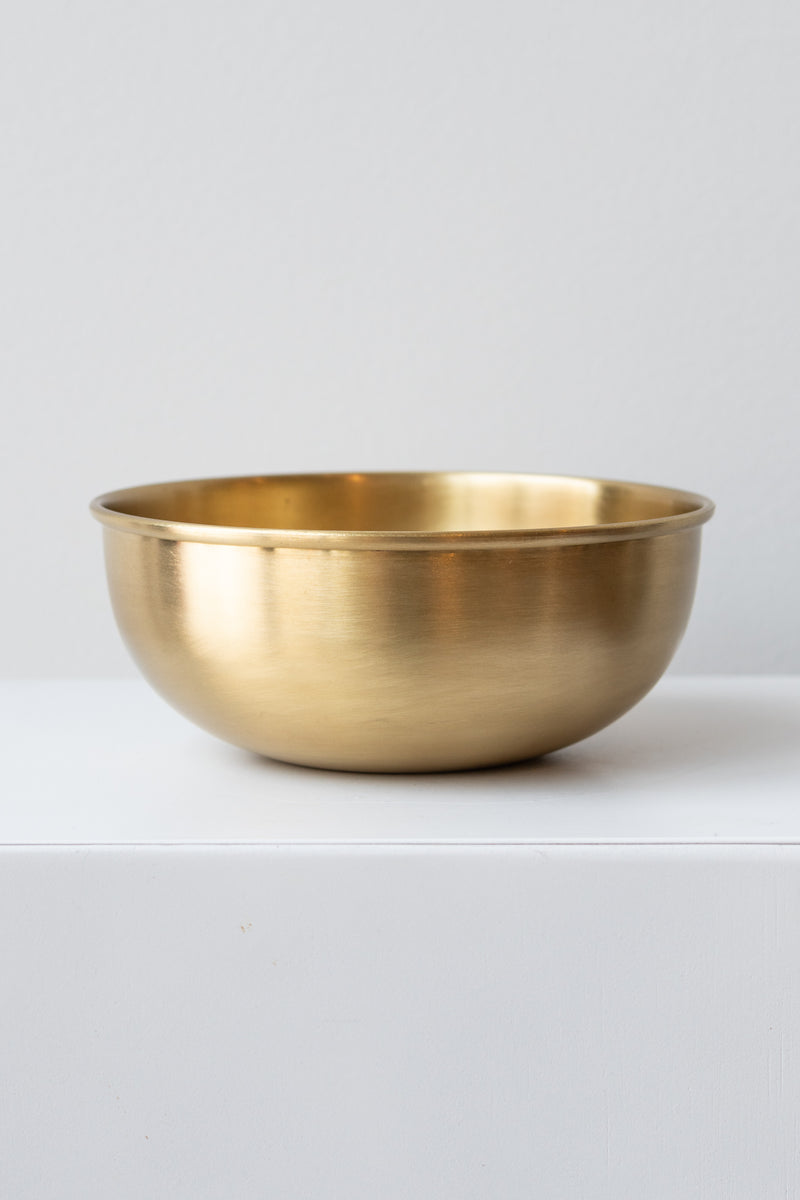 Extra Large brass bowl by Fog Linen Work sits on white surface in a white room