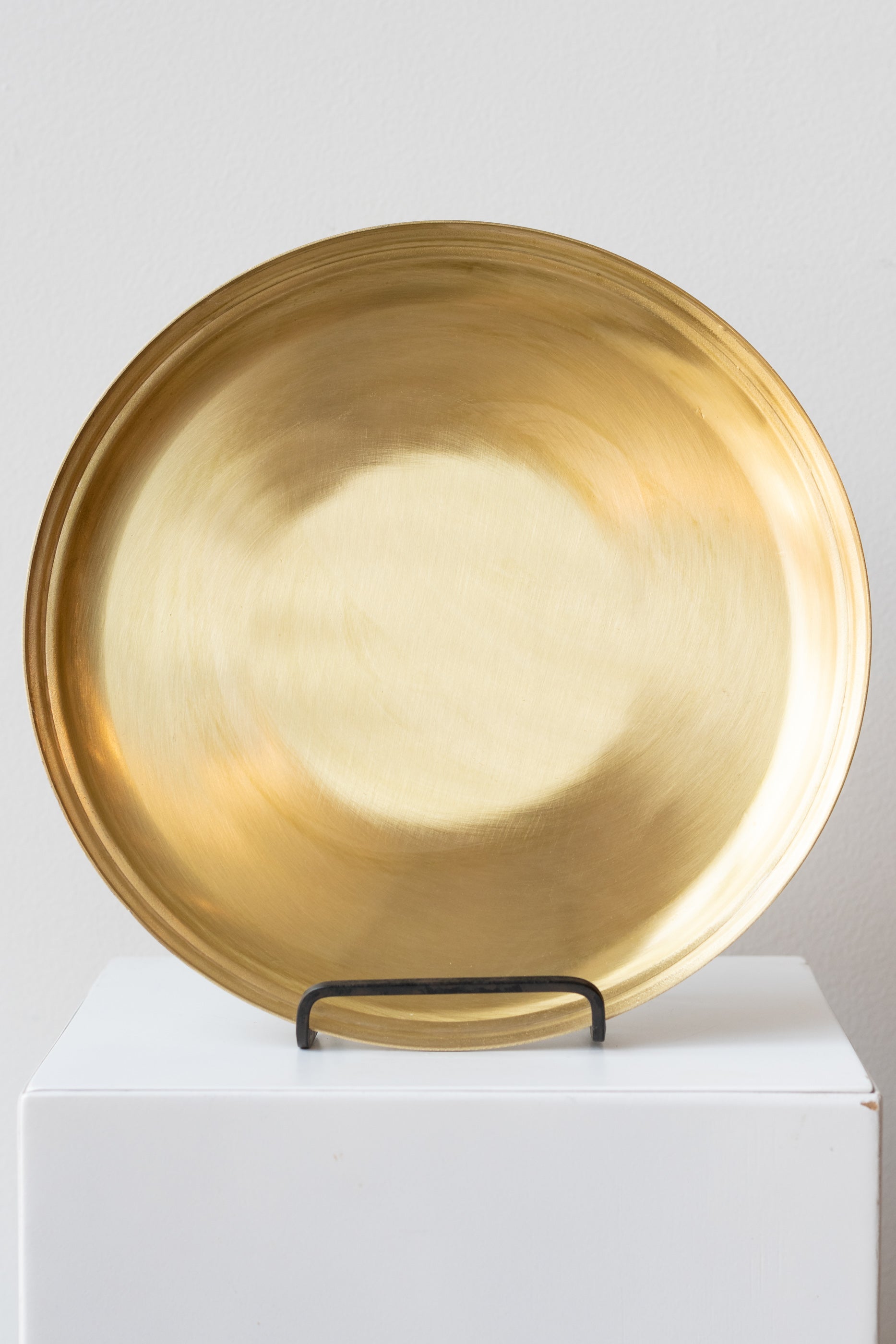 Brass serving tray by Fog Linen Work in black iron plate stand on a white surface in a white room