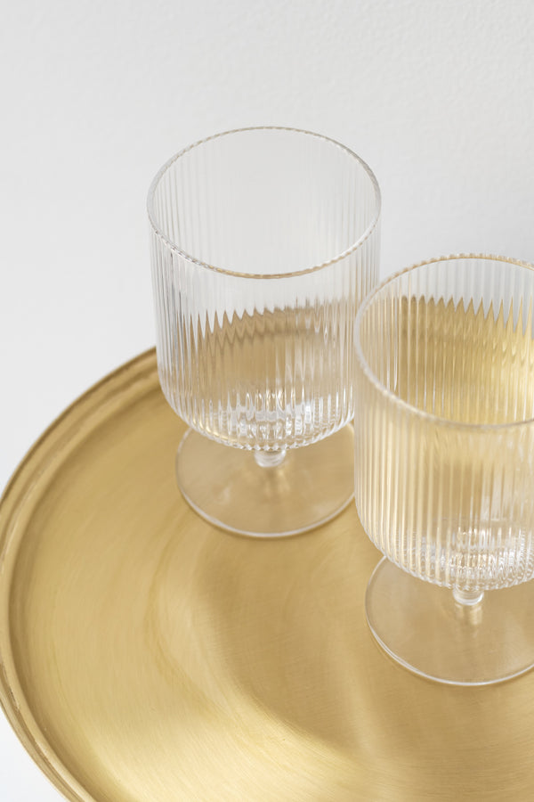 Close up of Fog Linen Work round brass serving tray with two rippled wine glasses sitting on top