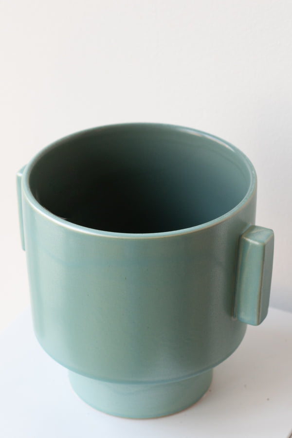 A slight overhead view of the matte aqua ~7" pot featuring the lip against a white background