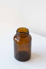 A slightly overhead angled view of the 120cc amber glass bottle against a white backdrop
