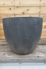 Jesslyn Pot fiberstone grey large against a wooden wall