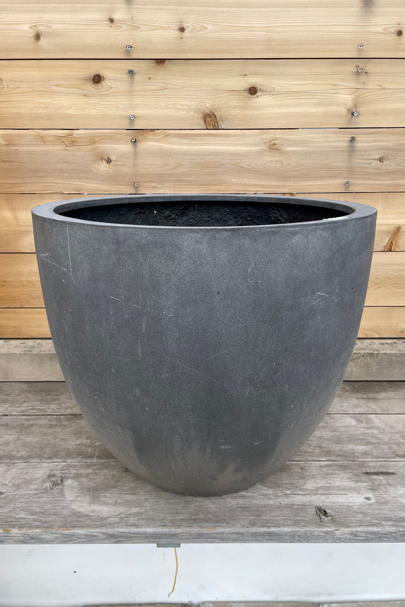 Detail of Jesslyn Pot fiberstone grey large against a wooden wall