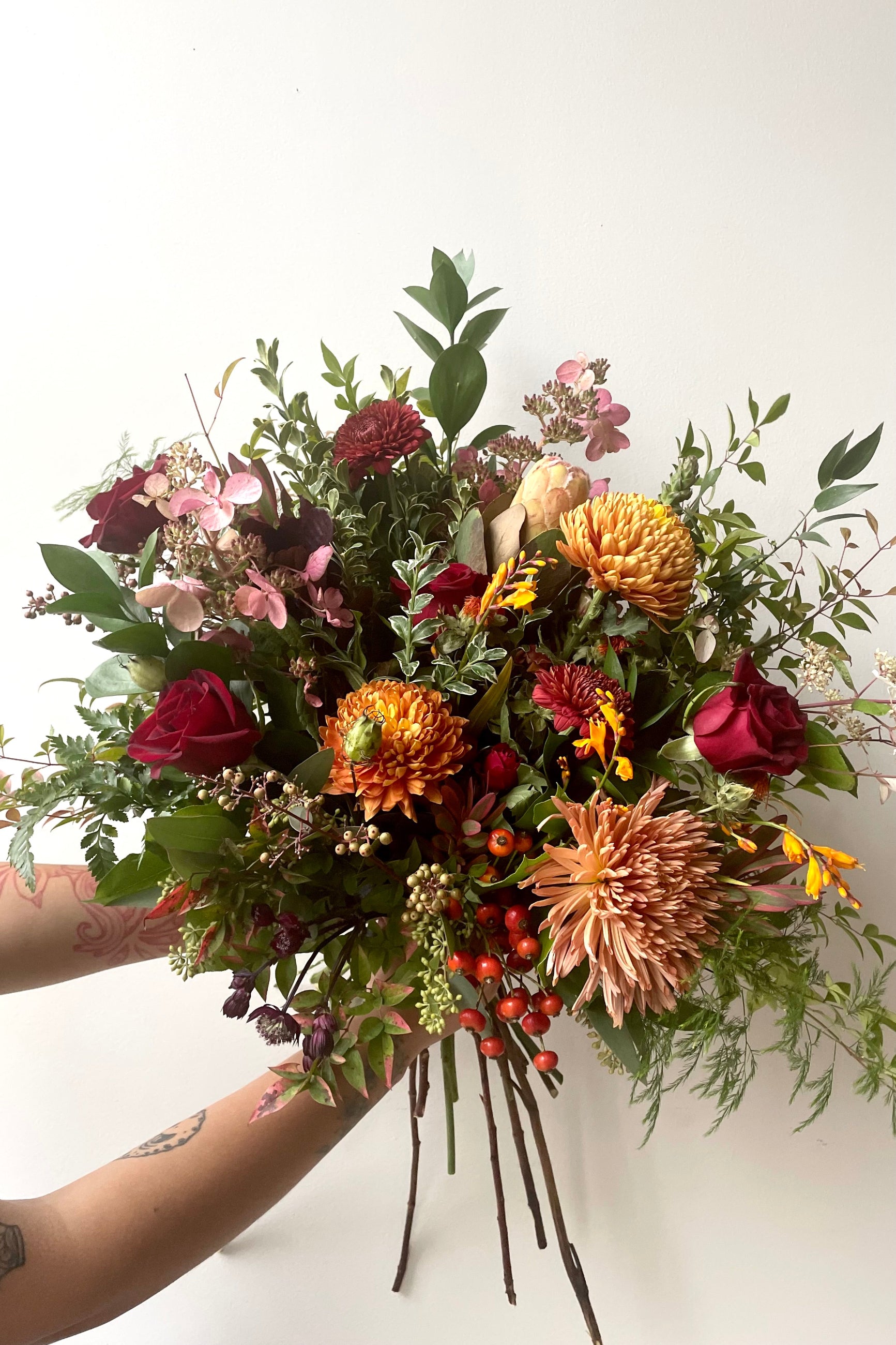Hands hold an example of fresh Floral Arrangement Earth with mums, berries and roses from Sprout Home Floral in Chicago ©Sprout Home #size_$200