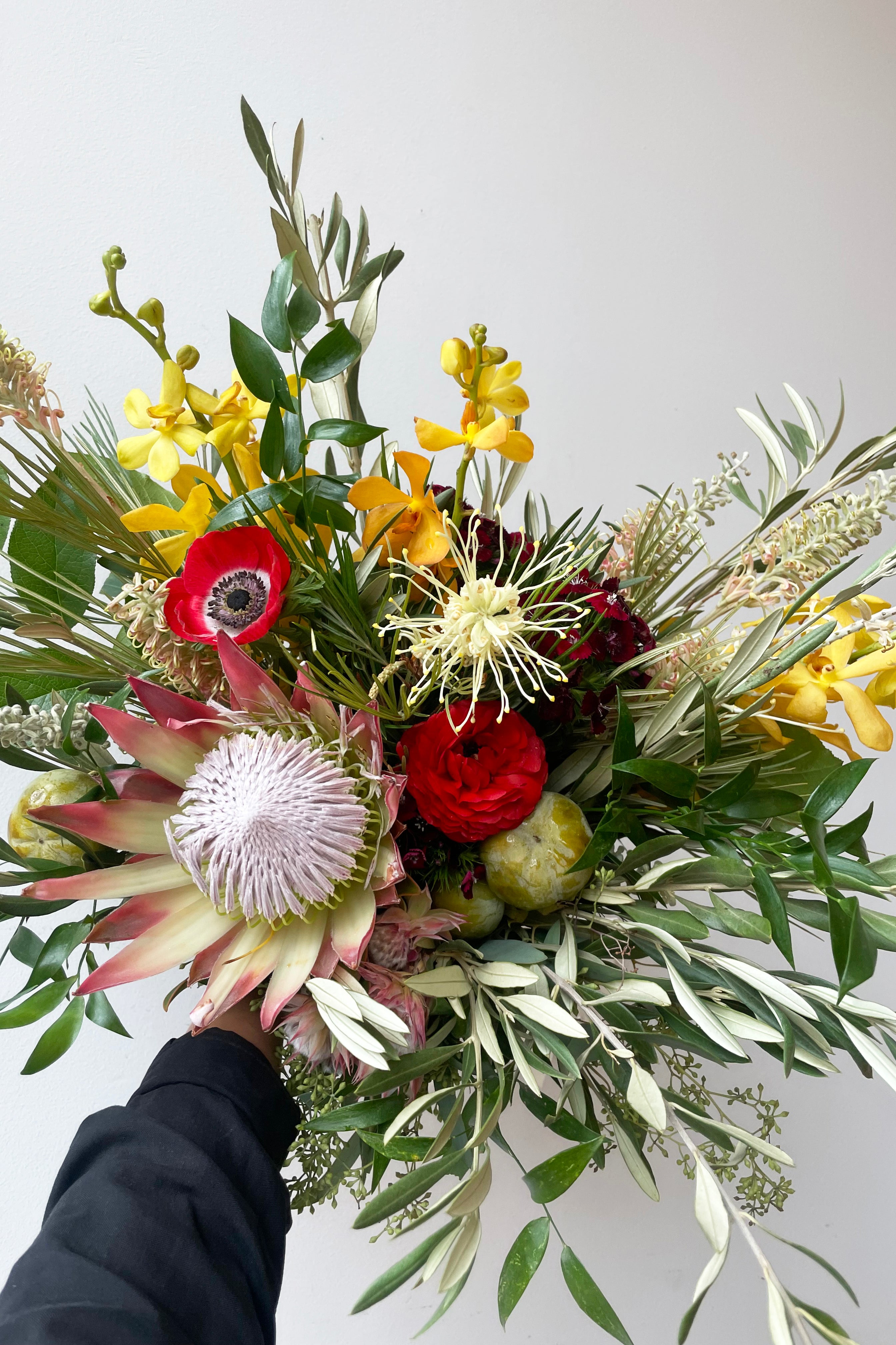 A hand holds an example of fresh Floral Arrangement Earth at the $160 price from Sprout Home Floral in Chicago #size_$160