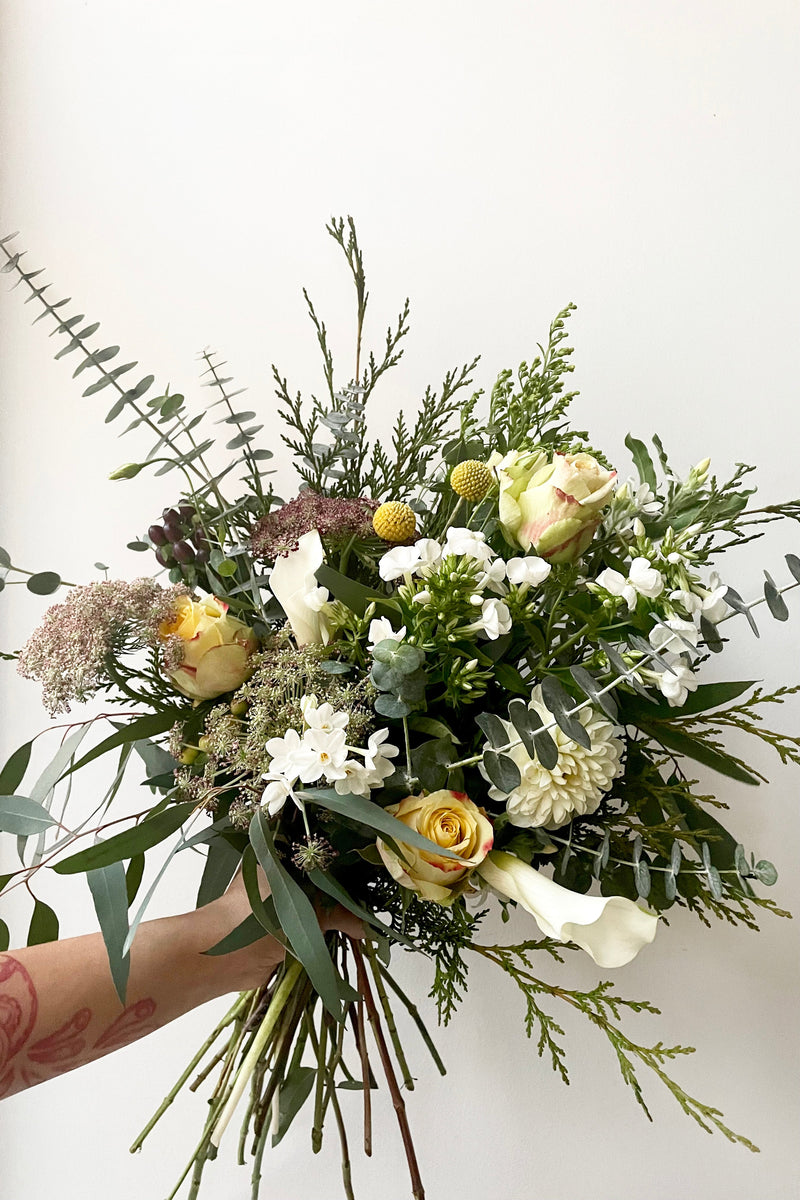 A hand holds an example of fresh Floral Arrangement Champagne Toast for $125 from Sprout Home Floral in Chicago