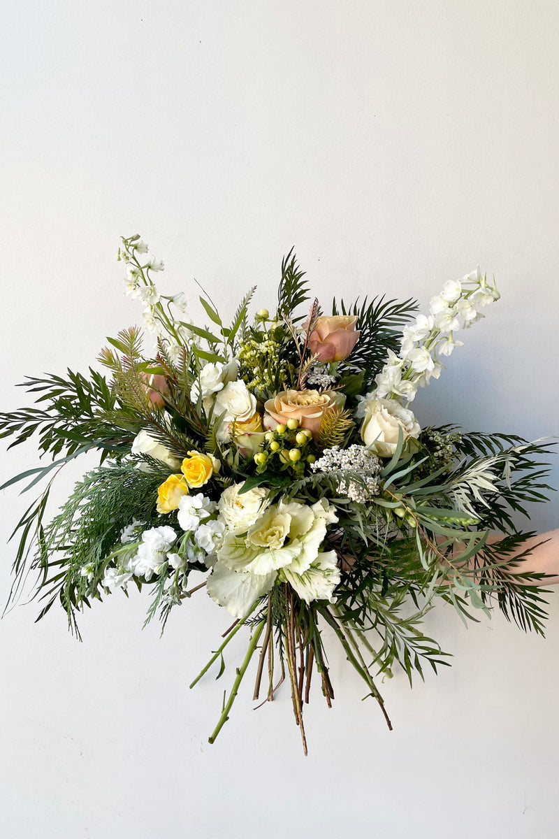 A hand holds fresh Floral Arrangement Eggnog for $200 from Sprout Home Floral in Chicago