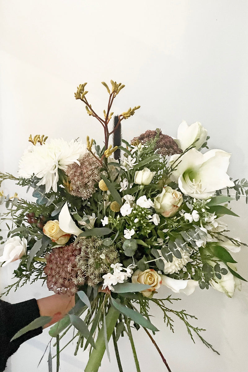 A hand holds fresh Floral Arrangement Champagne Toast for $200 from Sprout Home Floral in Chicago