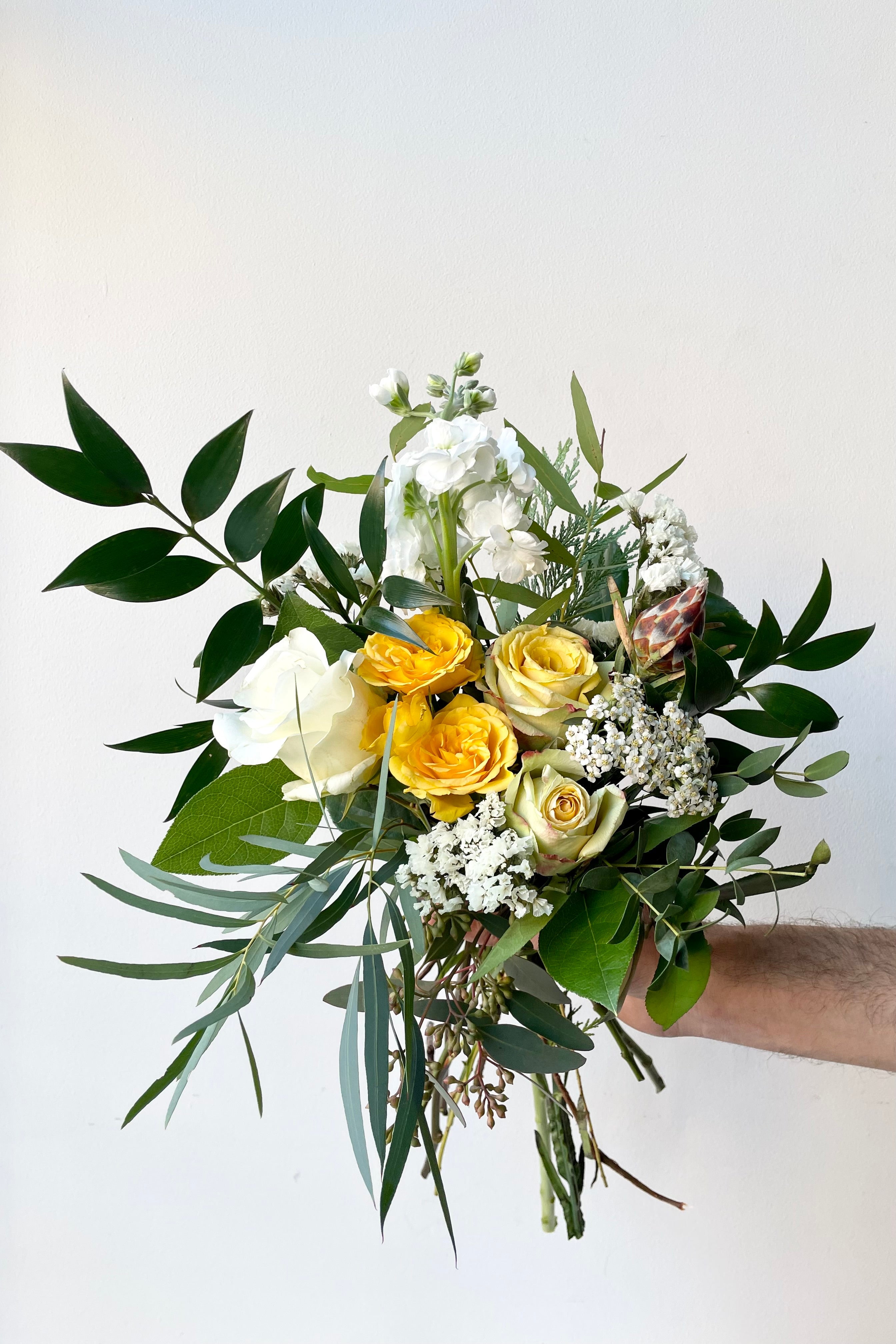 A hand holds fresh Floral Arrangement Champagne Toast for $65 from Sprout Home Floral in Chicago #size_$65