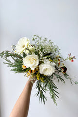 A hand holds an example of fresh Floral Arrangement Eggnog for $60 from Sprout Home Floral in Chicago