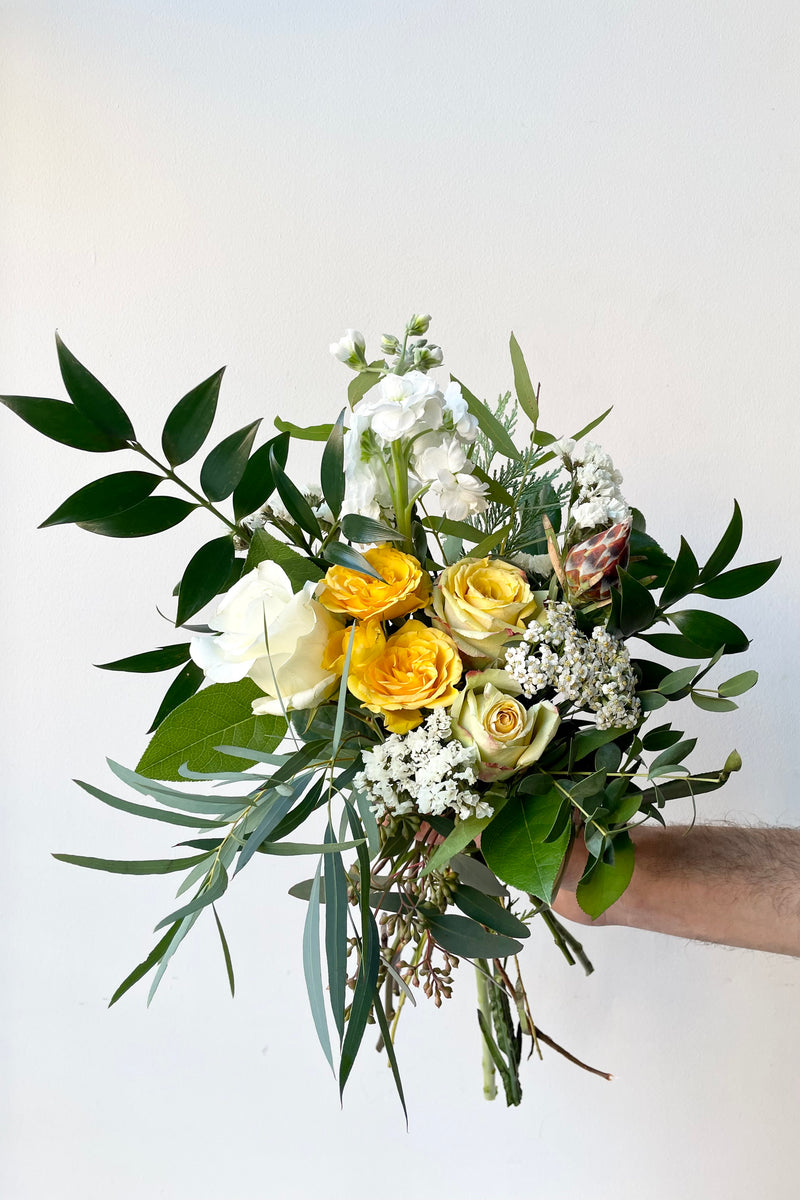 A hand holds fresh Floral Arrangement Eggnog for $60 from Sprout Home Floral in Chicago