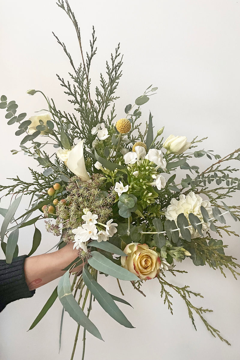 A hand holds an example of fresh Floral Arrangement Eggnog for $60 by Sprout Home Floral in Chicago